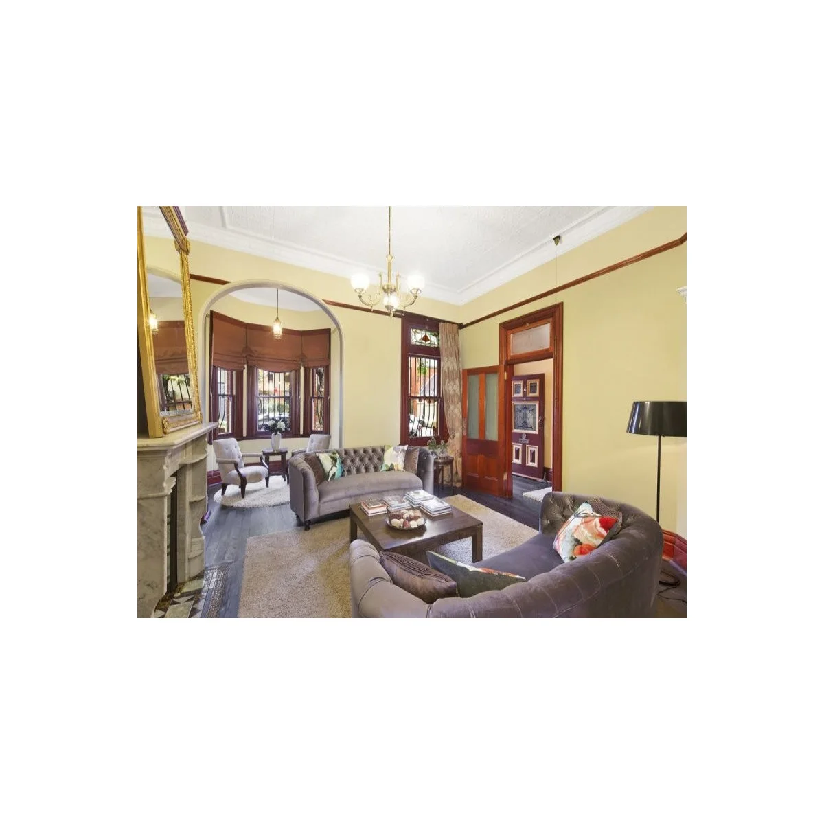 Edwardian terrace with gray tufted sofas and a small chair arrangement beyond an arch