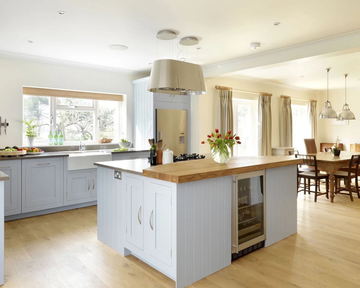 Blue kitchen with sink-window shades and long pale curtains at the dining area