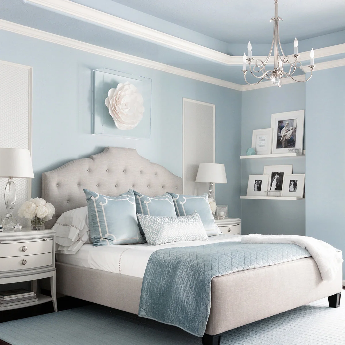 Powder blue bedroom with white horizontal trim, cream tufted bed, blue bedding accents and white picture ledges