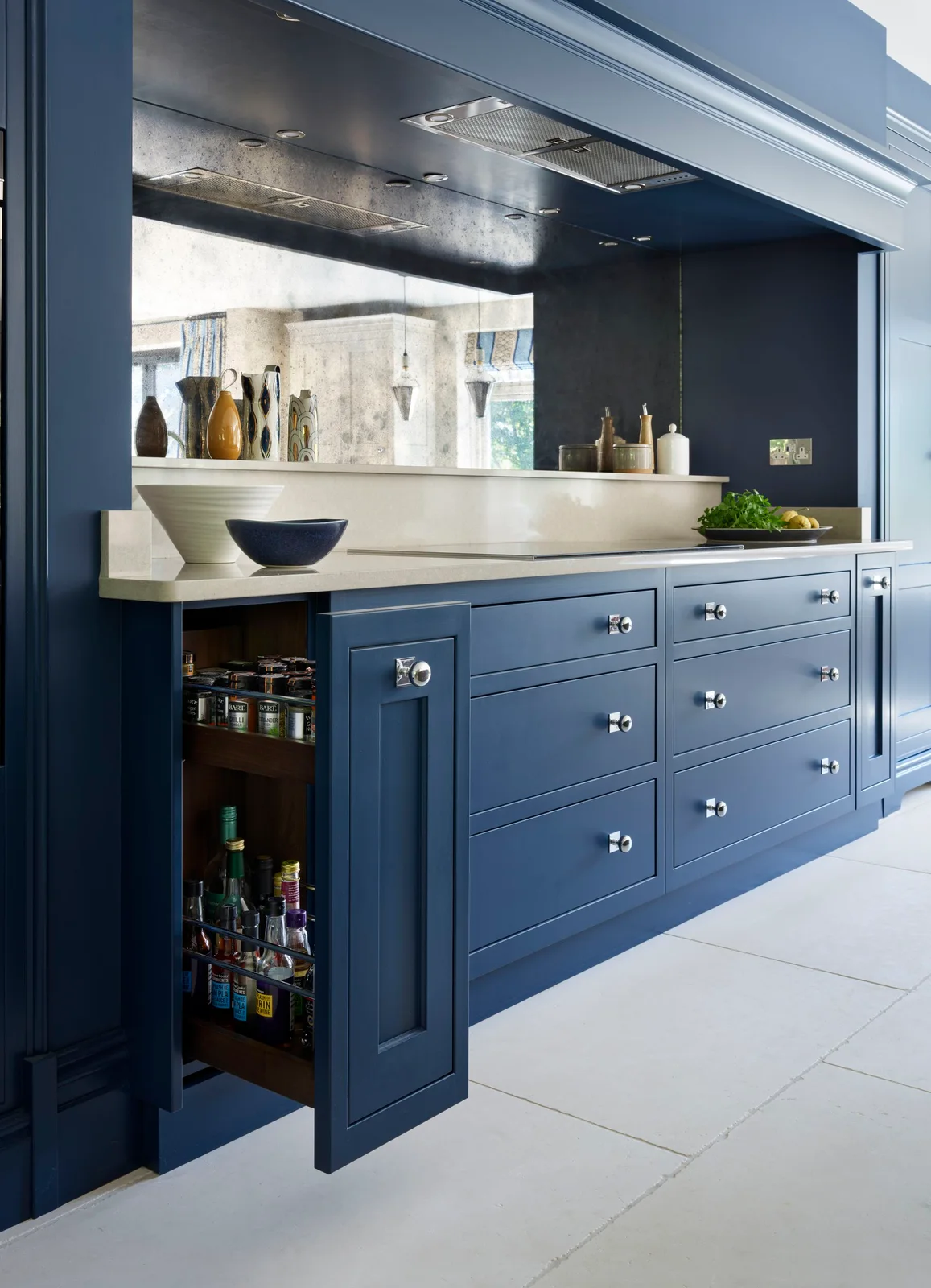 Navy kitchen with a narrow pull-out containing spice jars and taller bottles