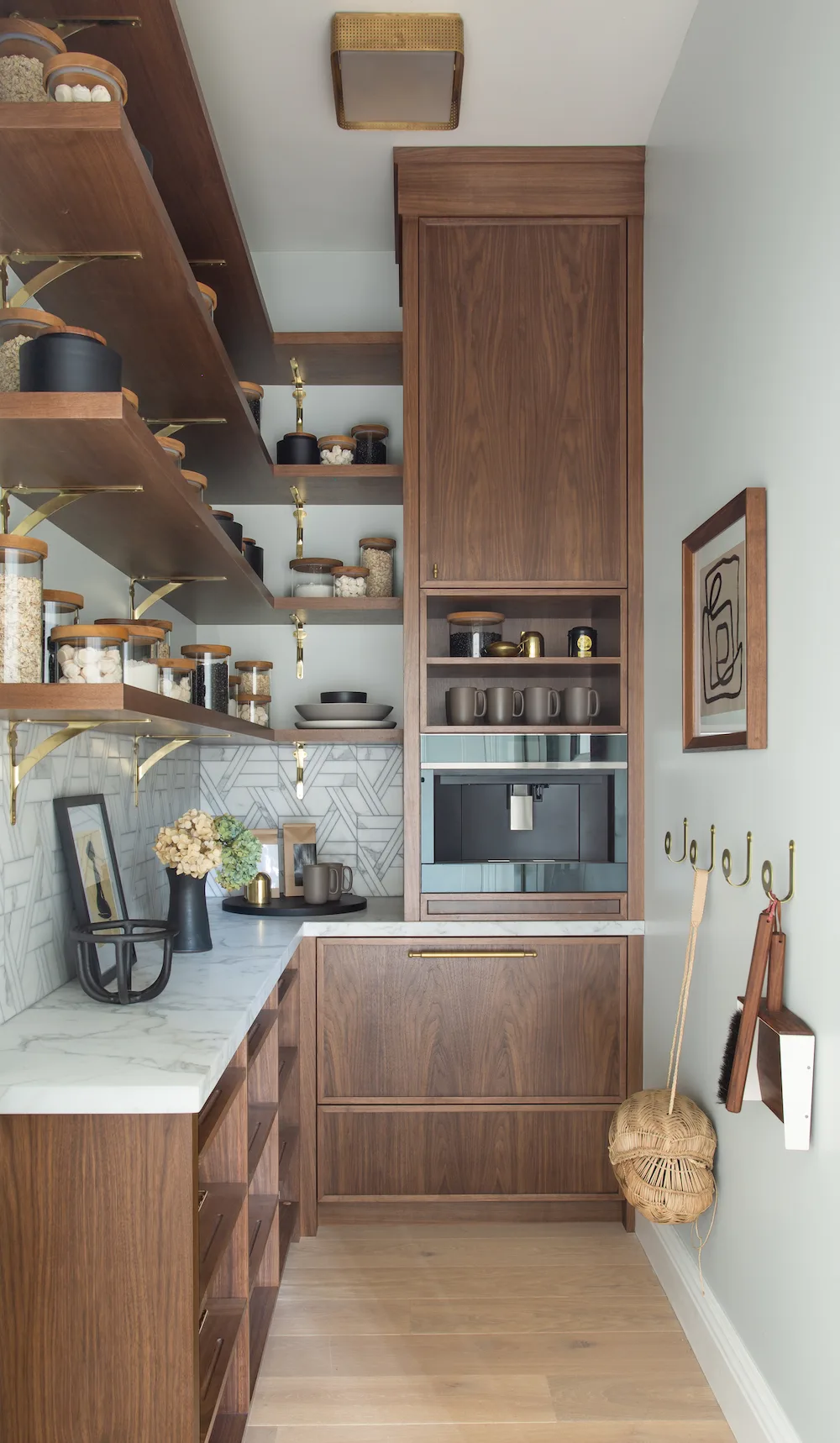 Narrow pantry with wood cabinets, open shelves, a built-in coffee machine and a pale counter.