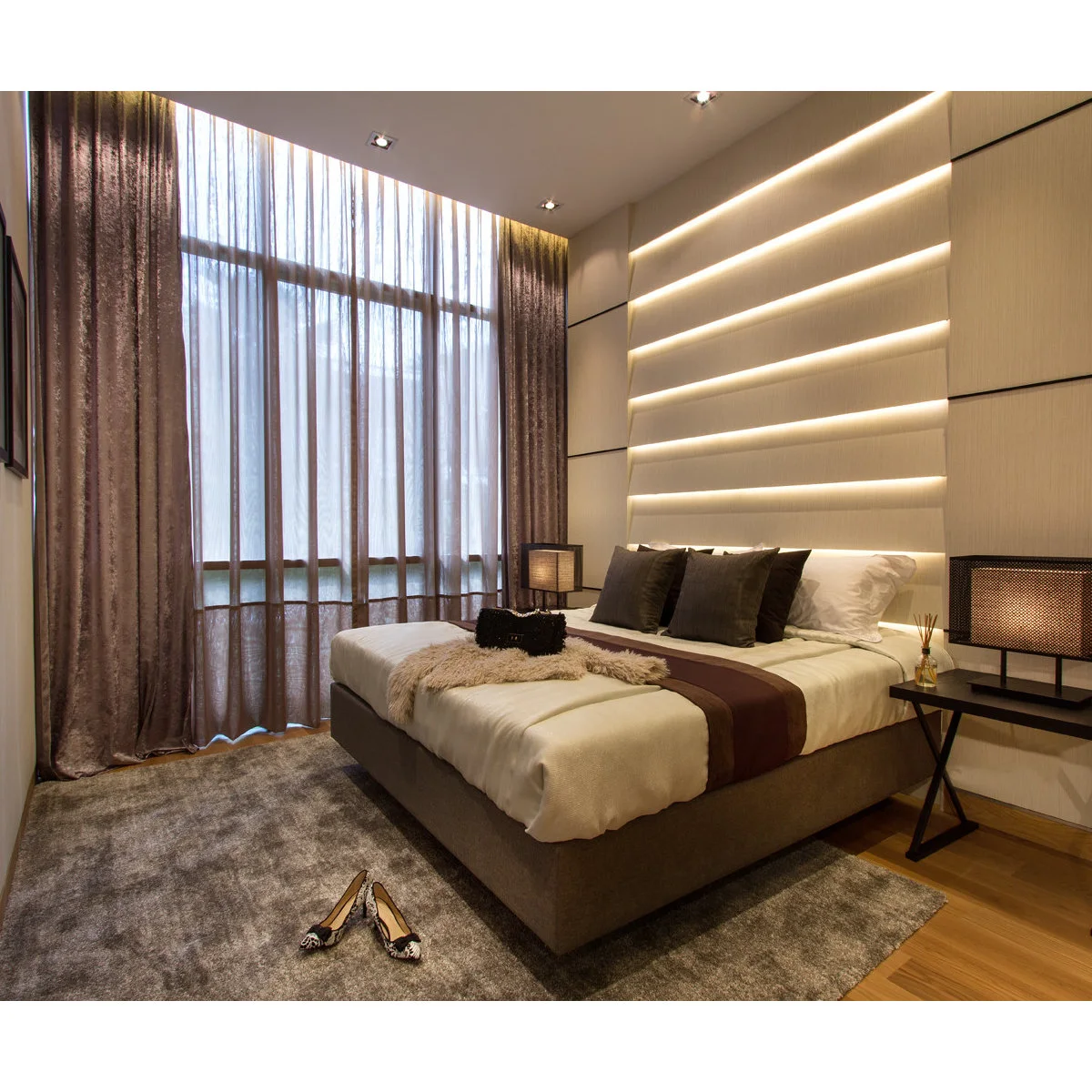 Brown side curtains and bed accents beside a tall sheer-covered window and a pale illuminated headboard wall.