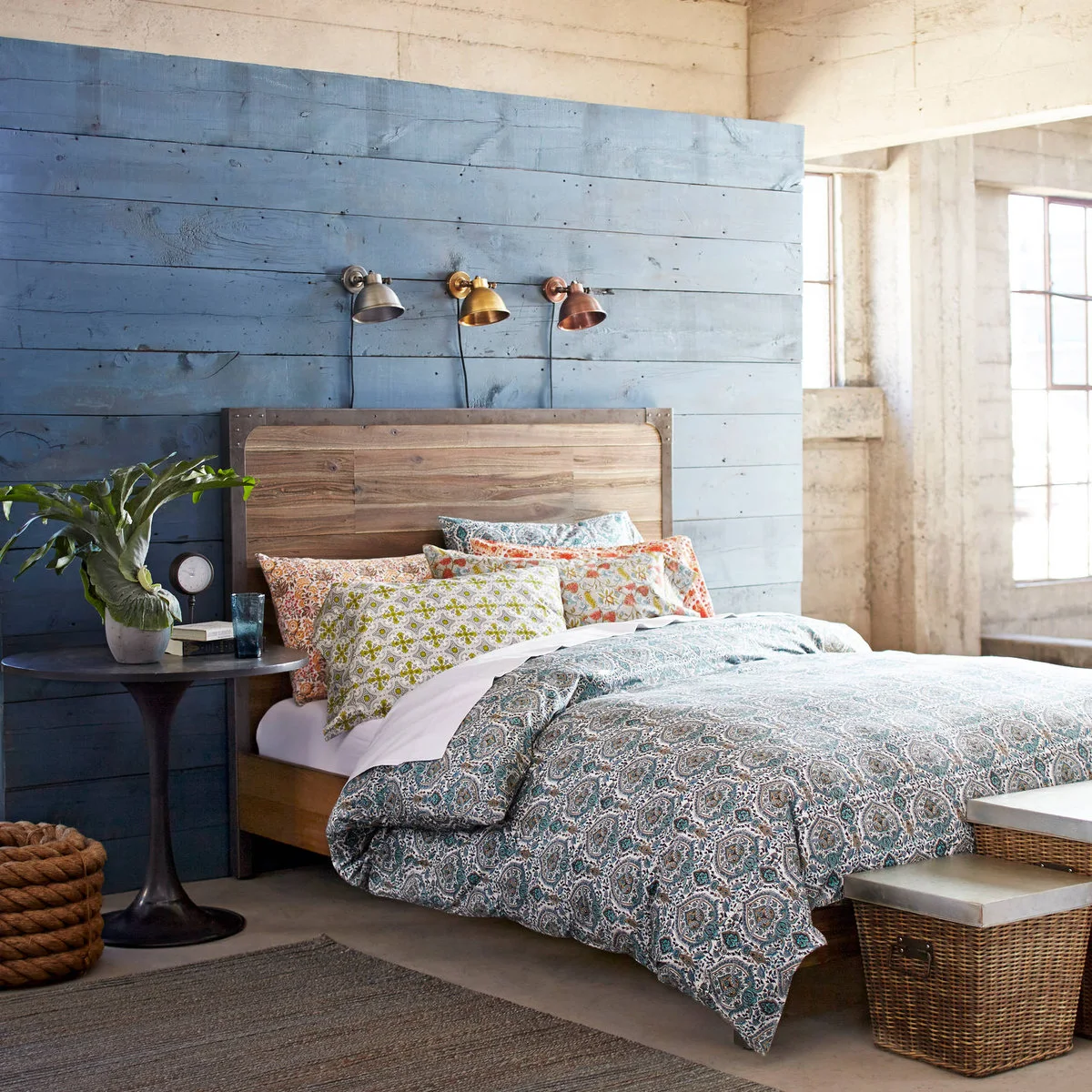 A dark gray textured rug appears in front of a wood bed with patterned blue bedding and a painted blue plank wall.