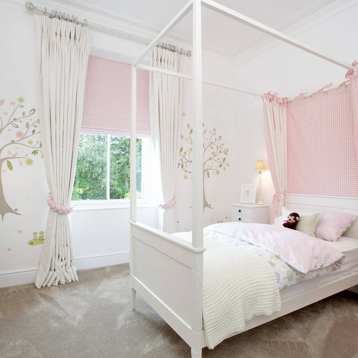 White four-poster bed with pale pink gingham panel and matching window blind