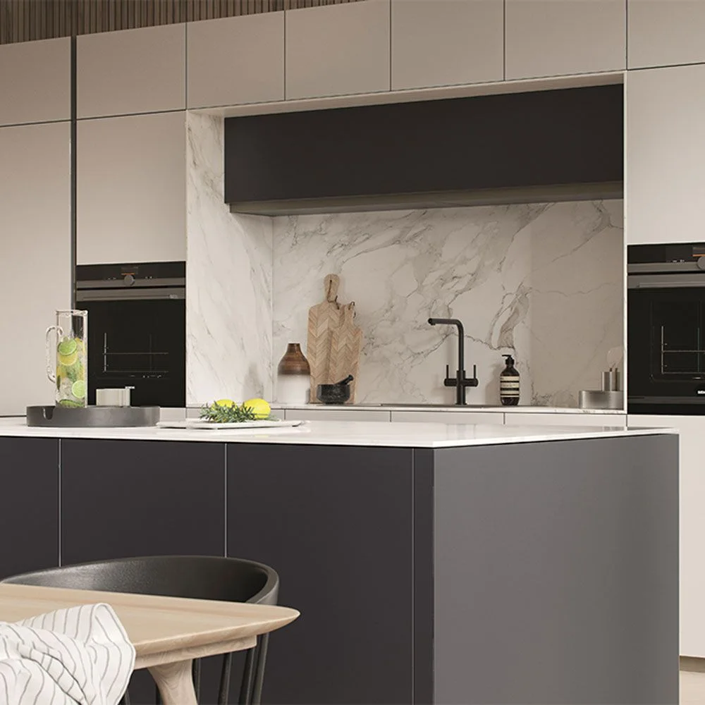 A kitchen has a pale veined working wall below a dark horizontal cabinet between pale tall cupboards beside dark ovens and a deeper island front