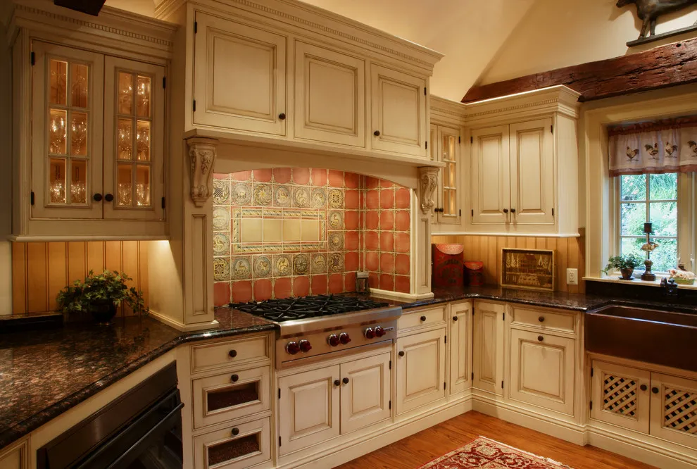 Cream cabinets with decorative moldings surround a warm tiled cooking alcove