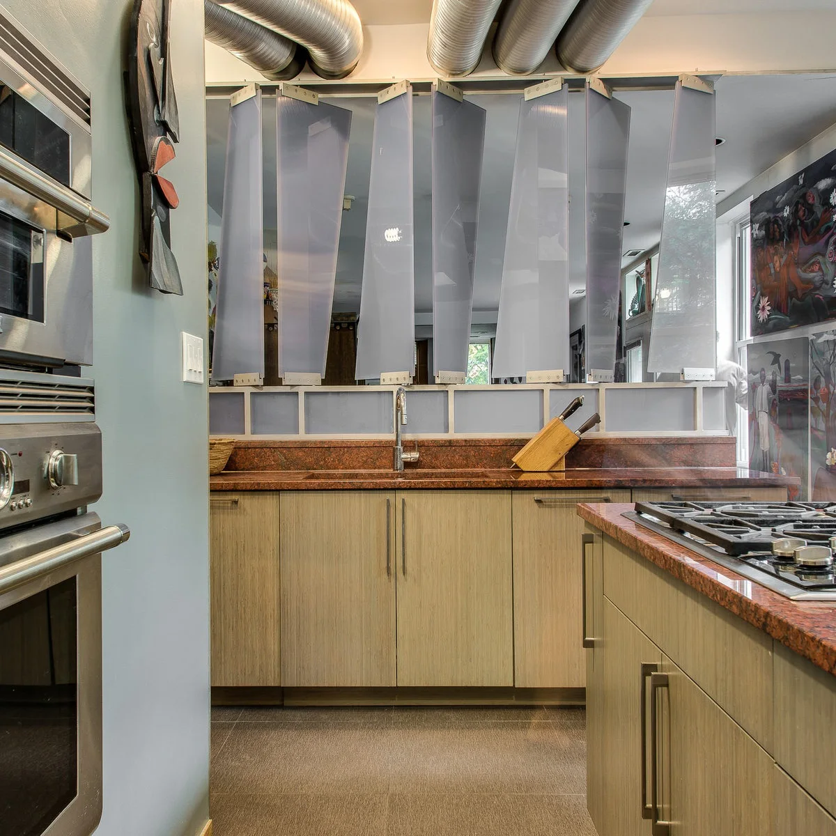 Angled translucent panels form a divider above a kitchen sink opposite a dining area.