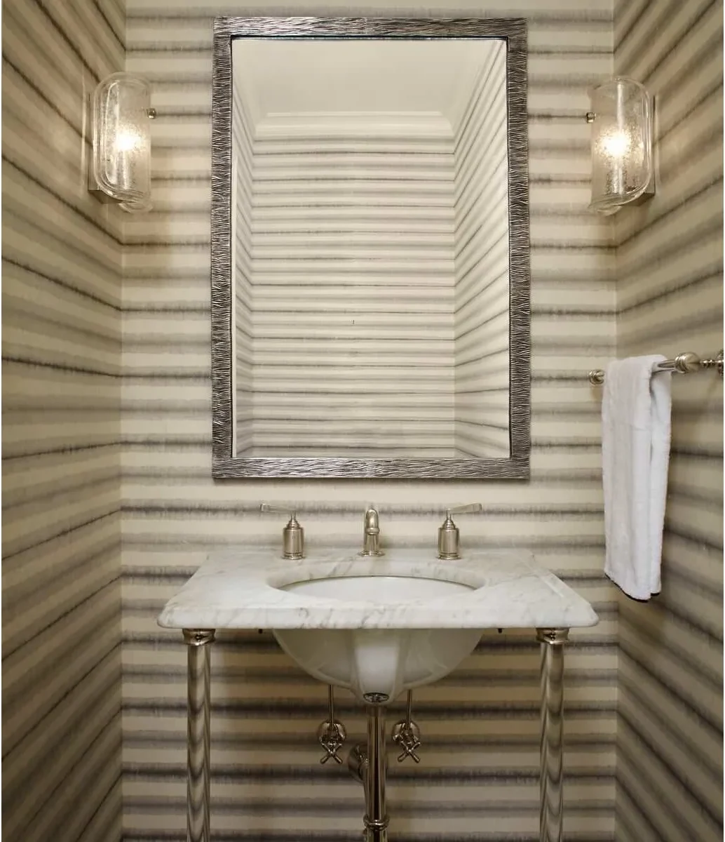 A short metal towel rail sits on the striped side wall beside a pale console sink and rectangular mirror.