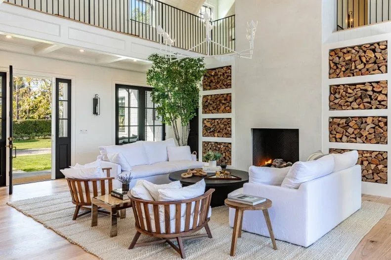 Tall pale fireplace wall with repeated fitted log compartments on both sides and white seating