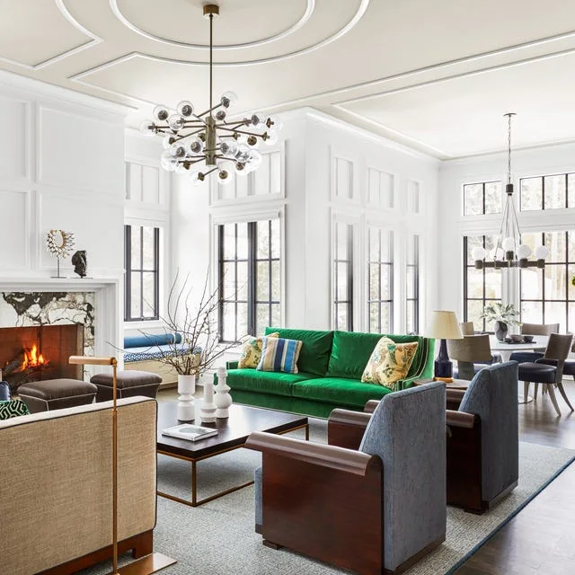 A bright green sofa faces a pale coffee table among dark chairs in a tall pale living room