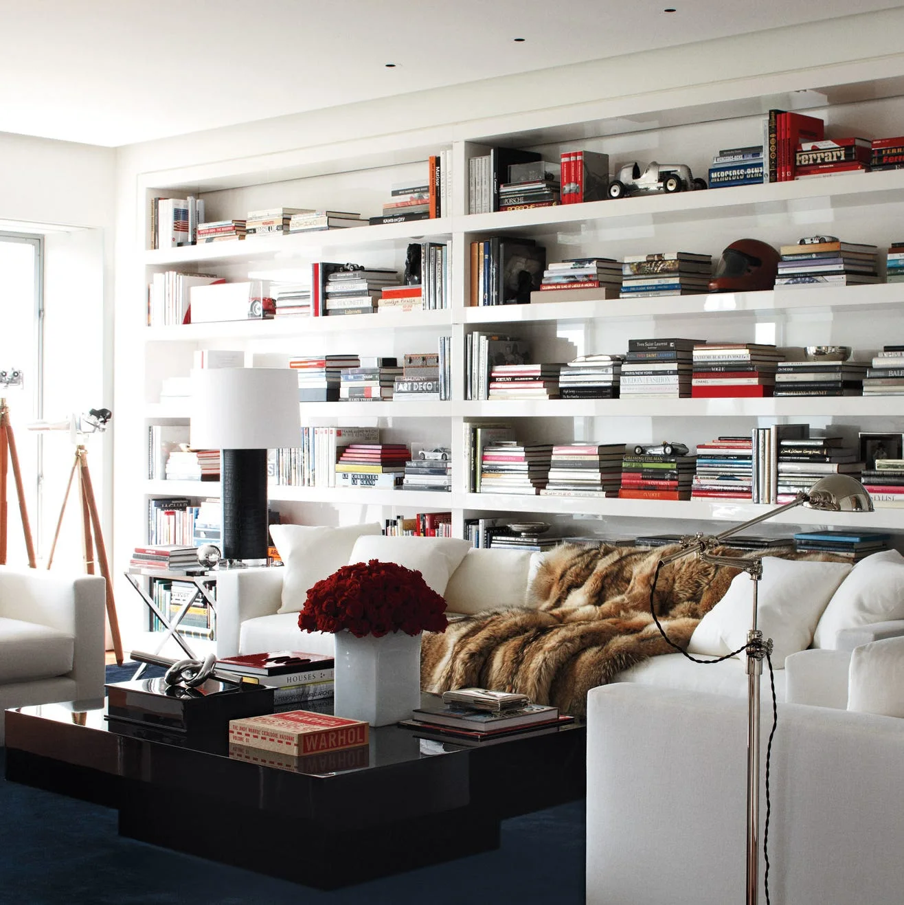 White living room with full-width book shelves, pale upholstered seating and a dark low coffee table