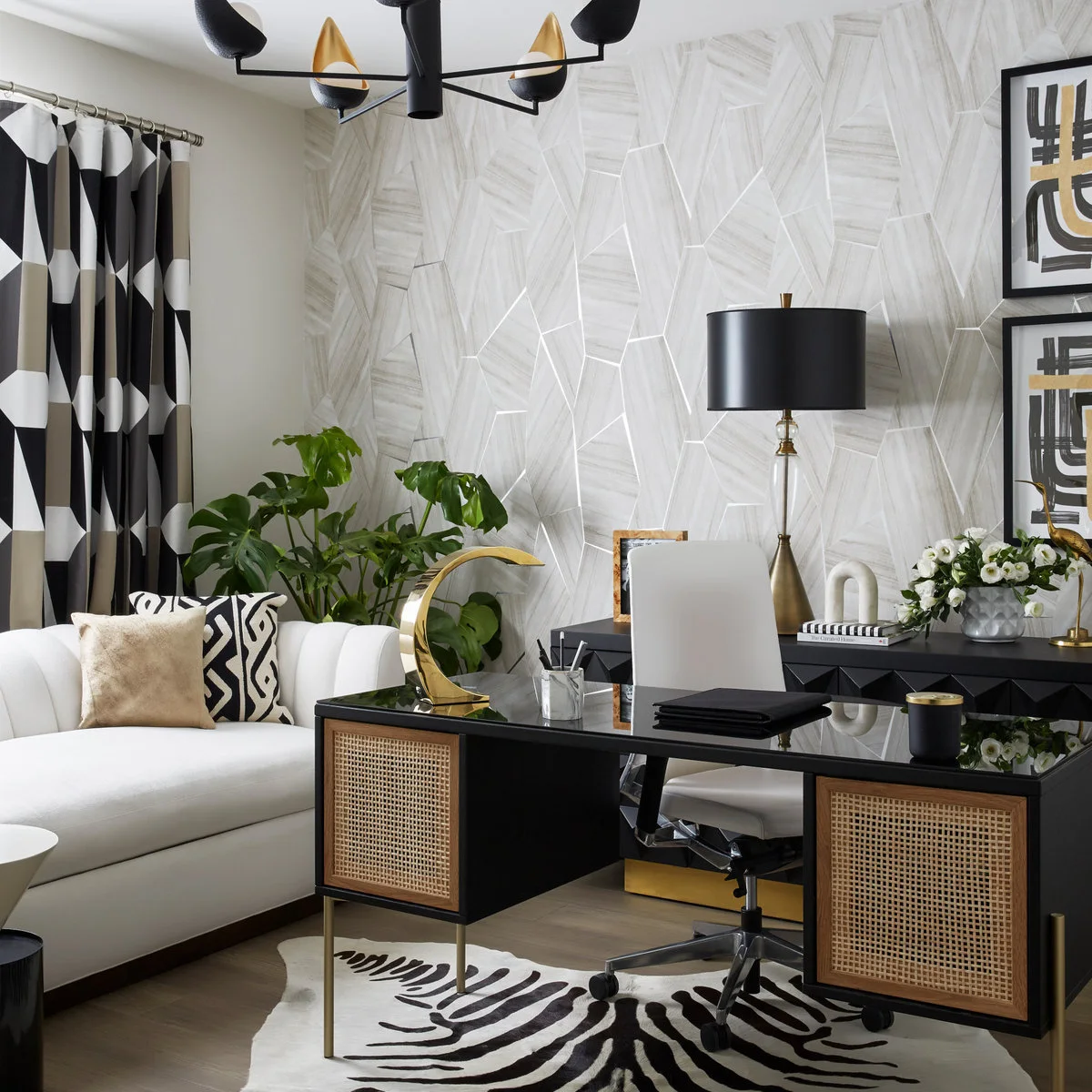 White sleeper sofa beside a black desk with woven-looking panels, patterned curtains and geometric wallpaper