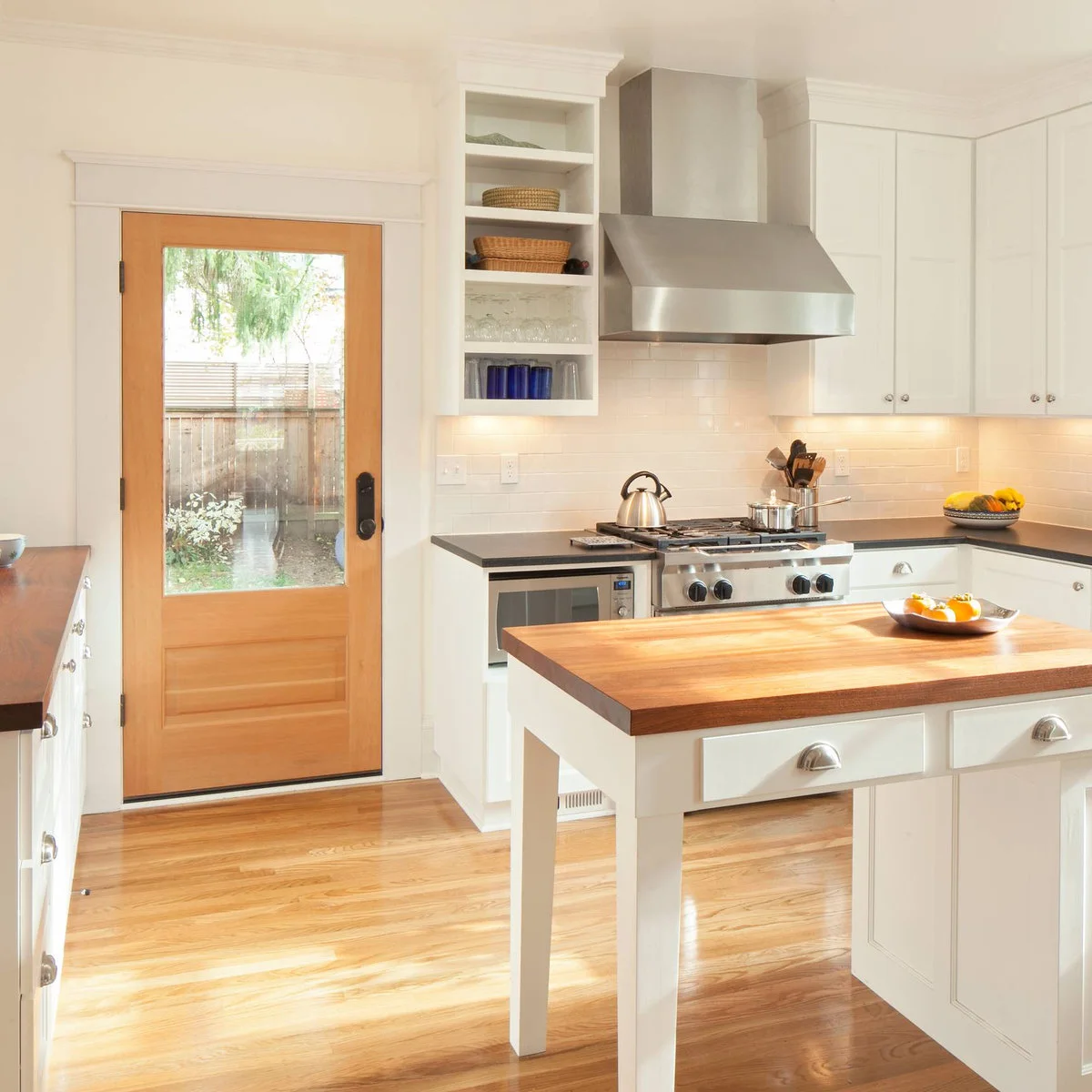 Small white kitchen island with a wood top, drawers and an open leg at one end