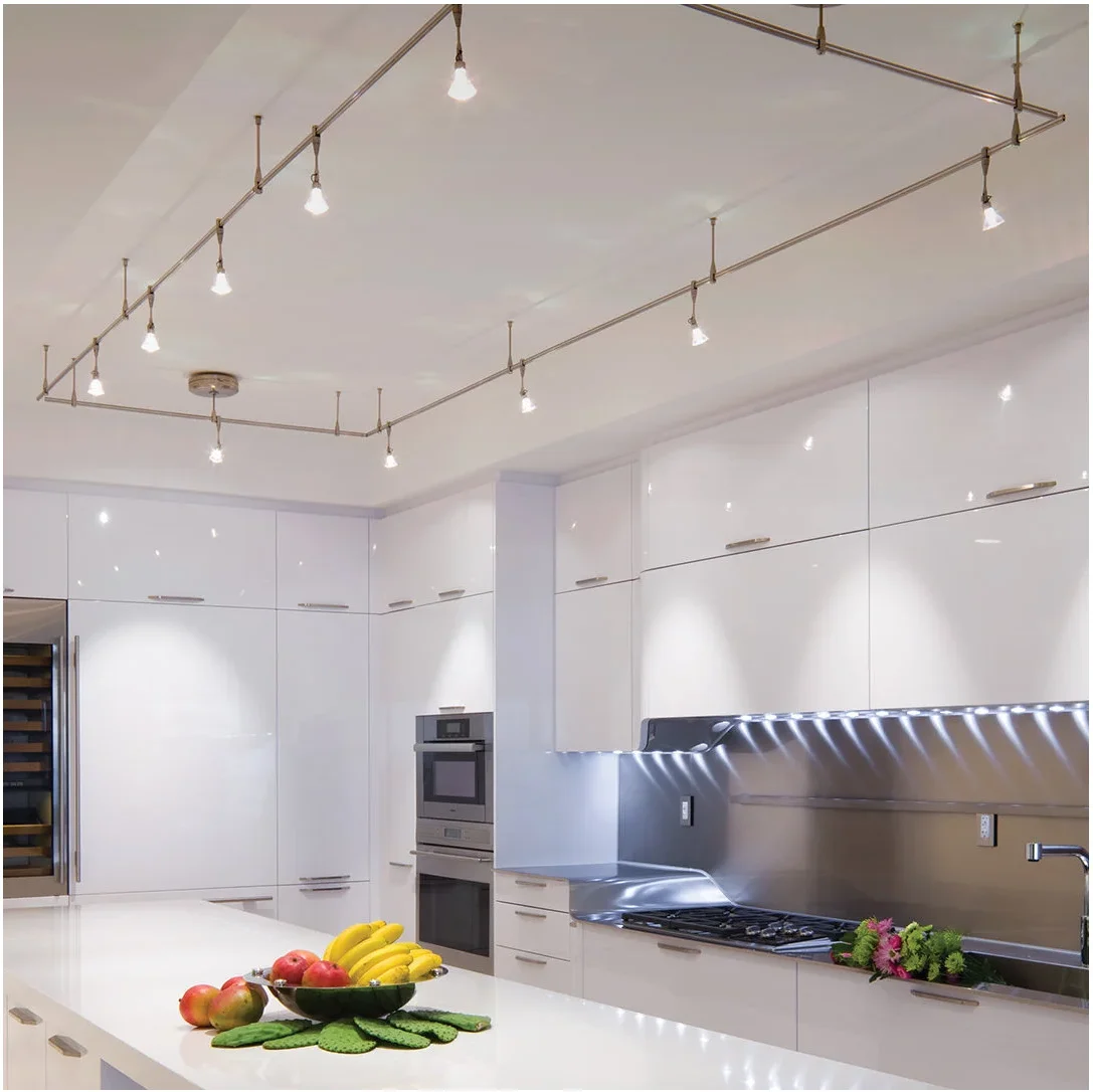 Slim metal lighting rails form a rectangular ceiling arrangement above glossy white cabinets and a reflective backsplash.