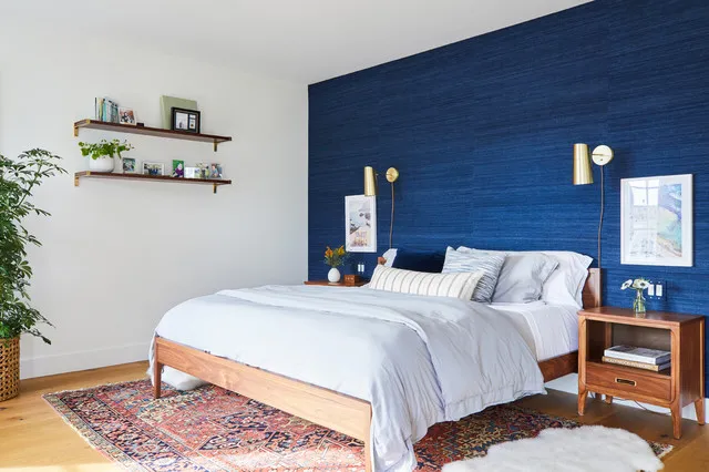 A textured navy wall stands behind white bedding and a warm timber bed frame.