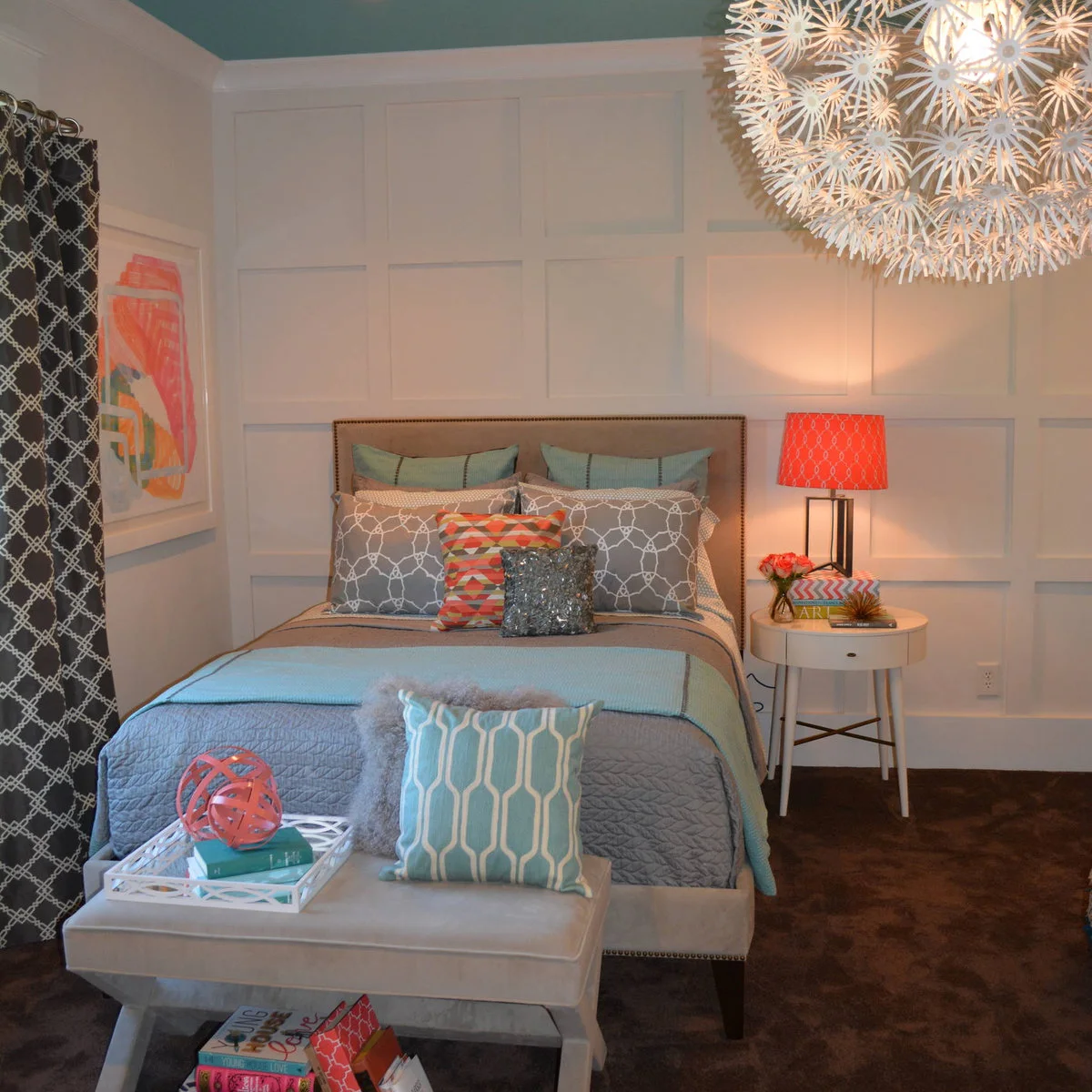 Teen bedroom with pale wall paneling, gray patterned curtains and bedding with coral and blue accents