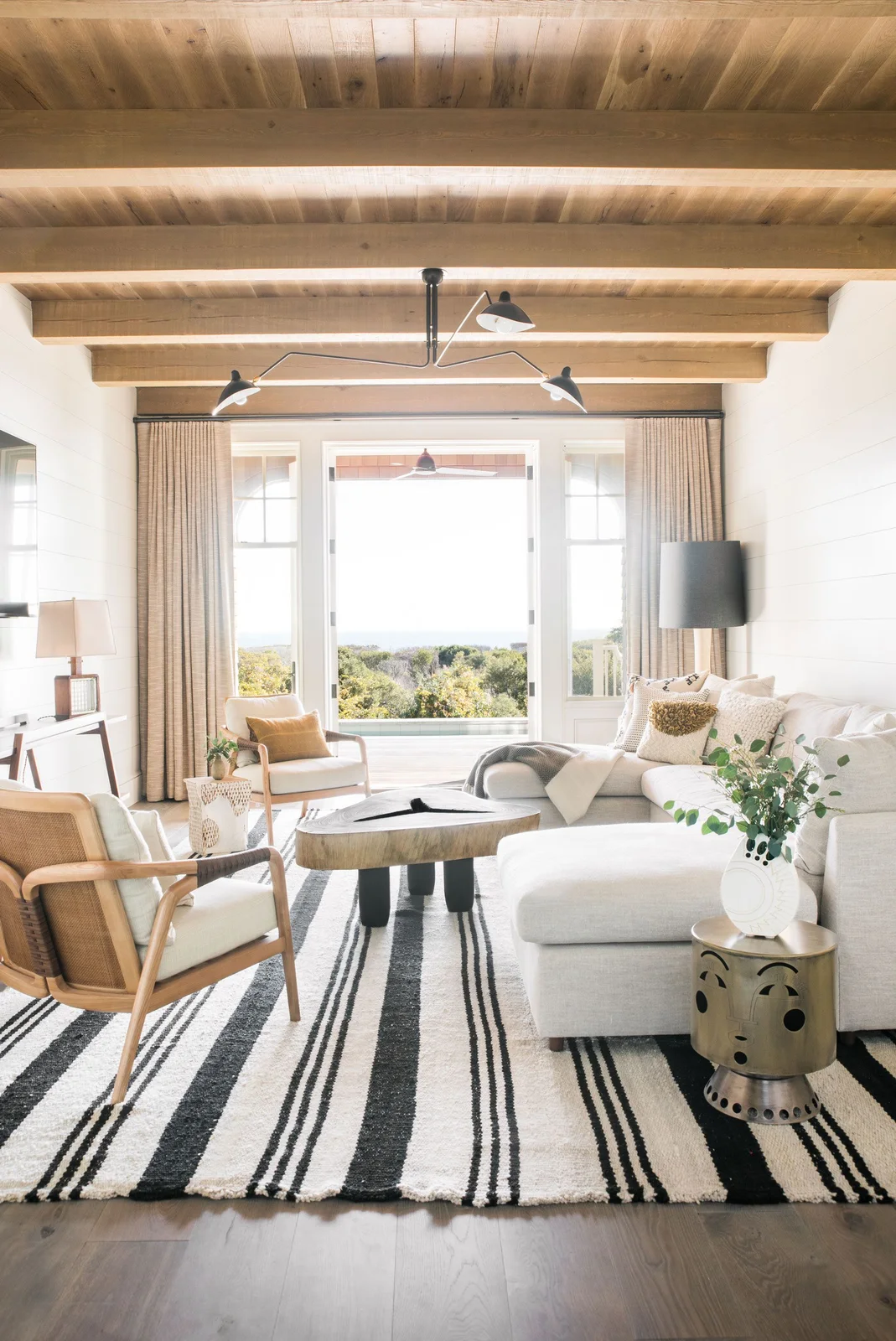 Thick irregular wooden coffee table left bare in a bright room with striped rug