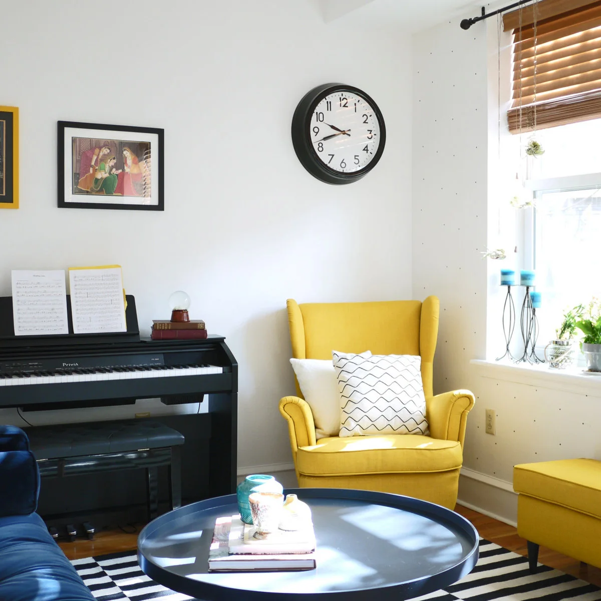 White living-room corner with a yellow armchair, small keyboard and dark round table