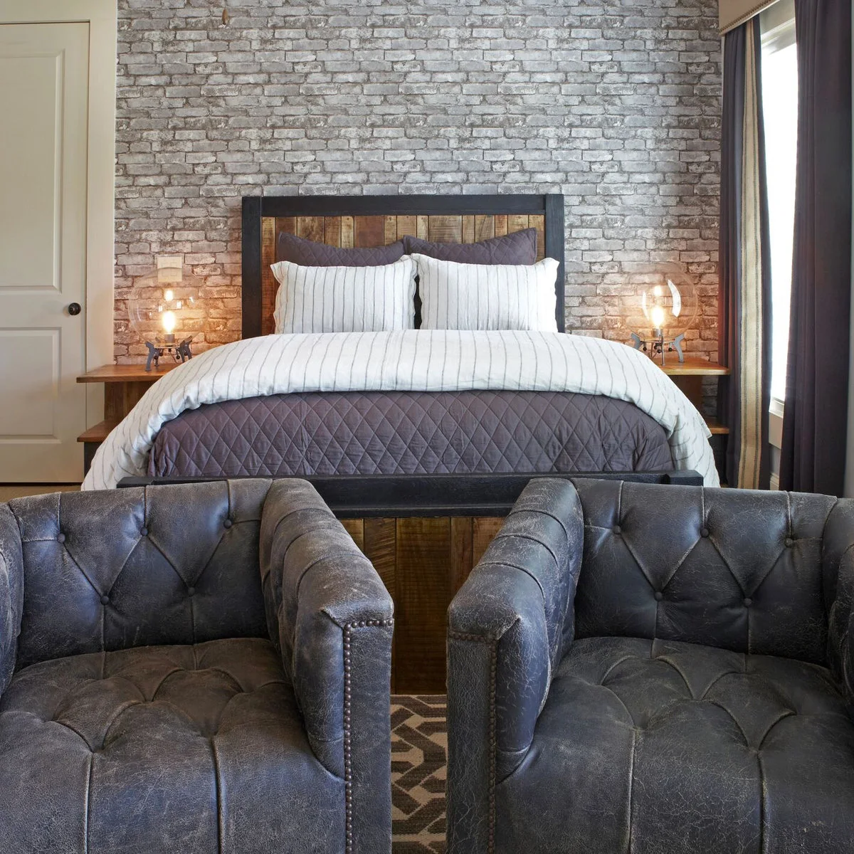 Teen bedroom with brick-effect bed wall and two dark upholstered chairs in the foreground