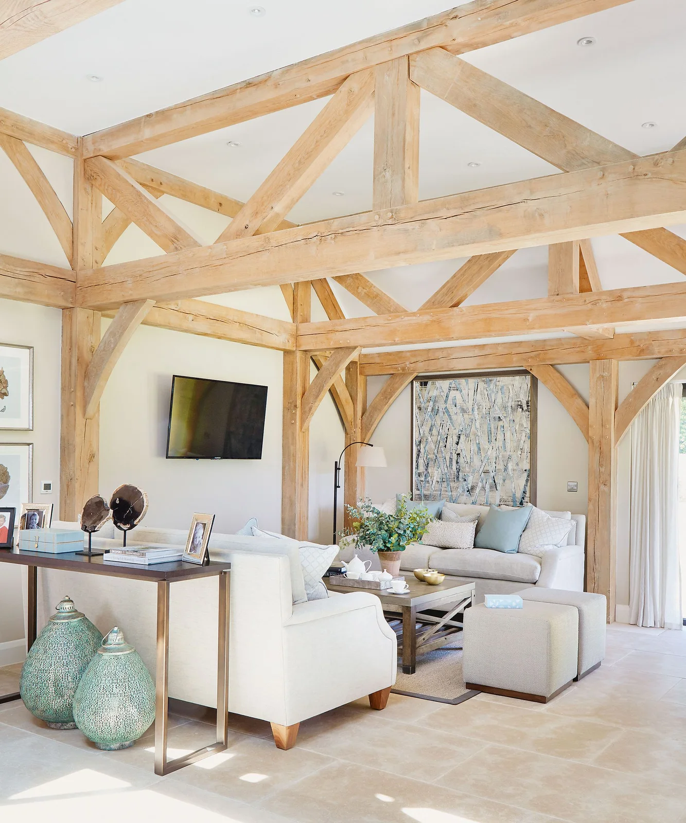 Wall-mounted TV between exposed timber posts in a bright country living room