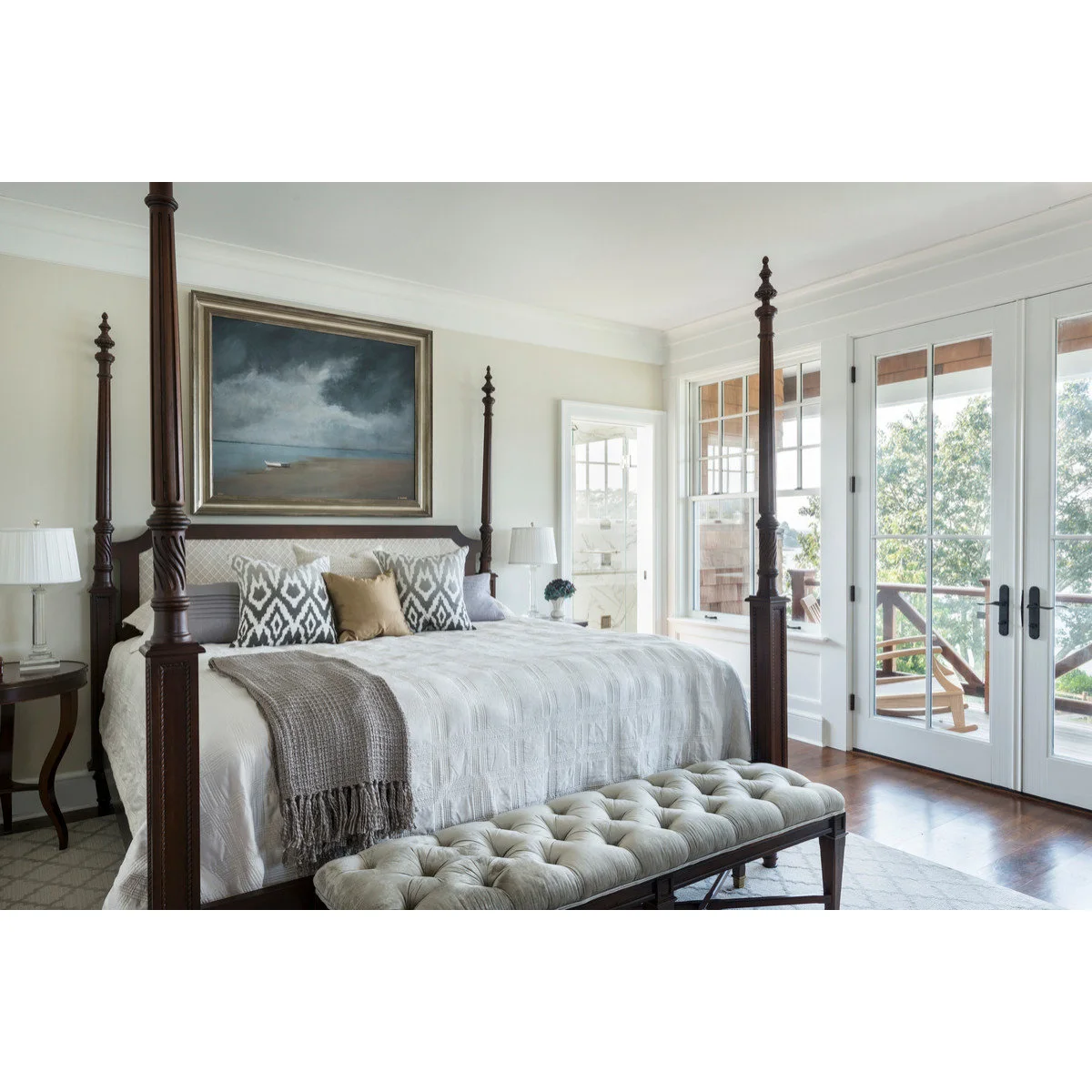 Long tufted pale bench with dark turned legs beside a dark four-poster bed