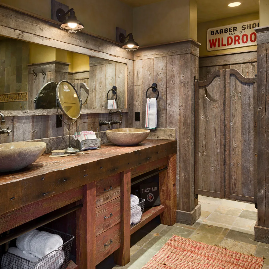 A rough timber double washstand with bowl sinks, open shelves and dark metal wall lights