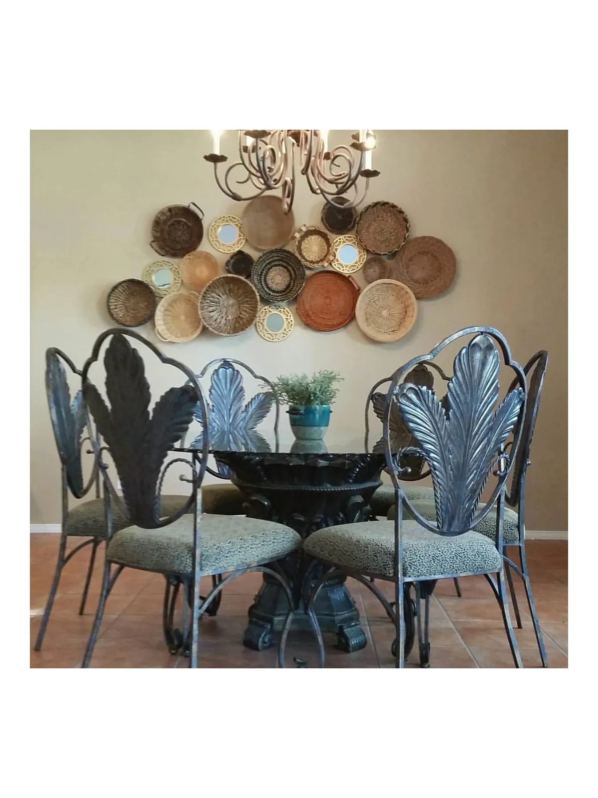 Blue sculptural chairs surround a dark round table beneath grouped woven baskets and a chandelier.