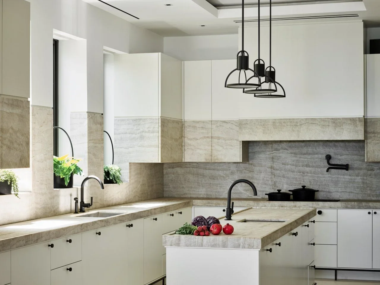 Plain white cabinet fronts sit beneath pale textured panels and black open pendants above a narrow island.