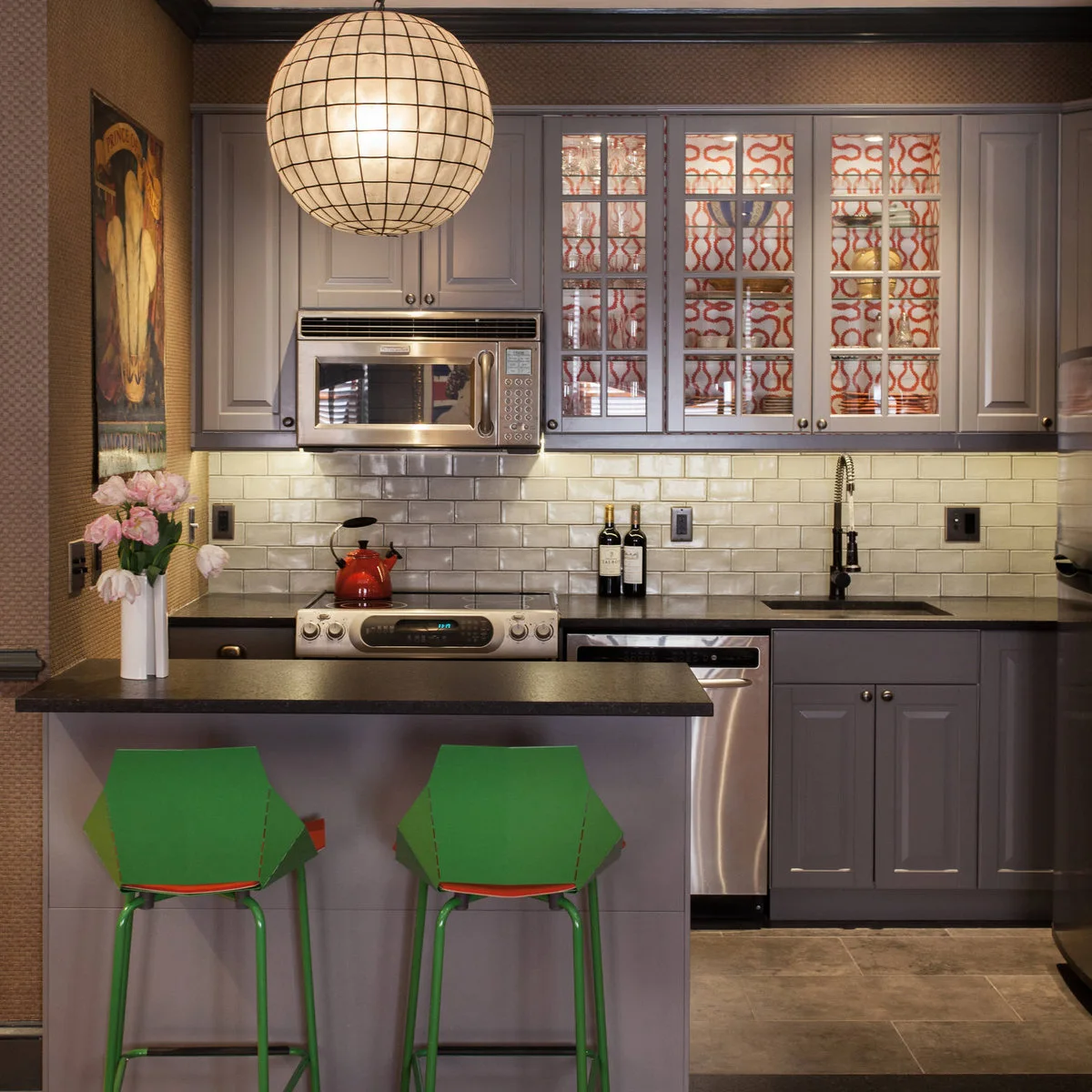 Compact purple kitchenette with a cooker, sink and microwave beside a peninsula with green chairs