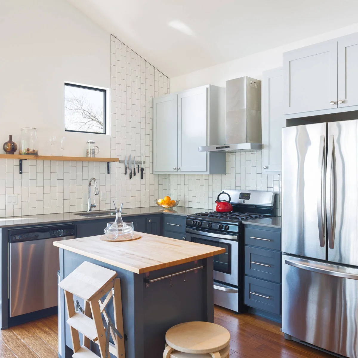 Small dark kitchen island with a wood top and a side rail in a blue-gray kitchen