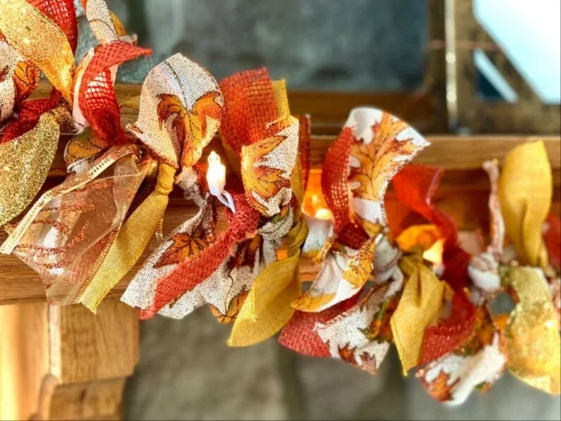 Red, yellow and patterned fabric strips form a garland along a wooden chair back with lighter tied details between them