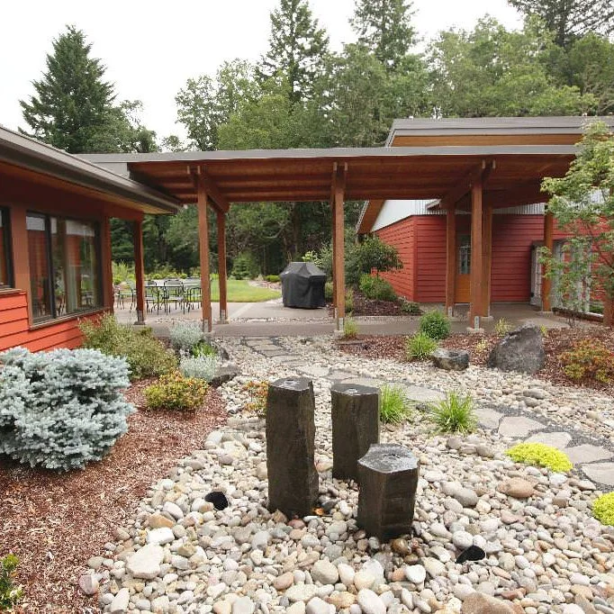 Three dark upright fountain stones stand in pale rounded rock beside a paved courtyard path