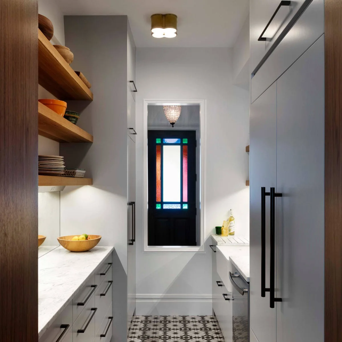 Compact gray galley with a tall cabinet near the entrance and open wooden shelves opposite