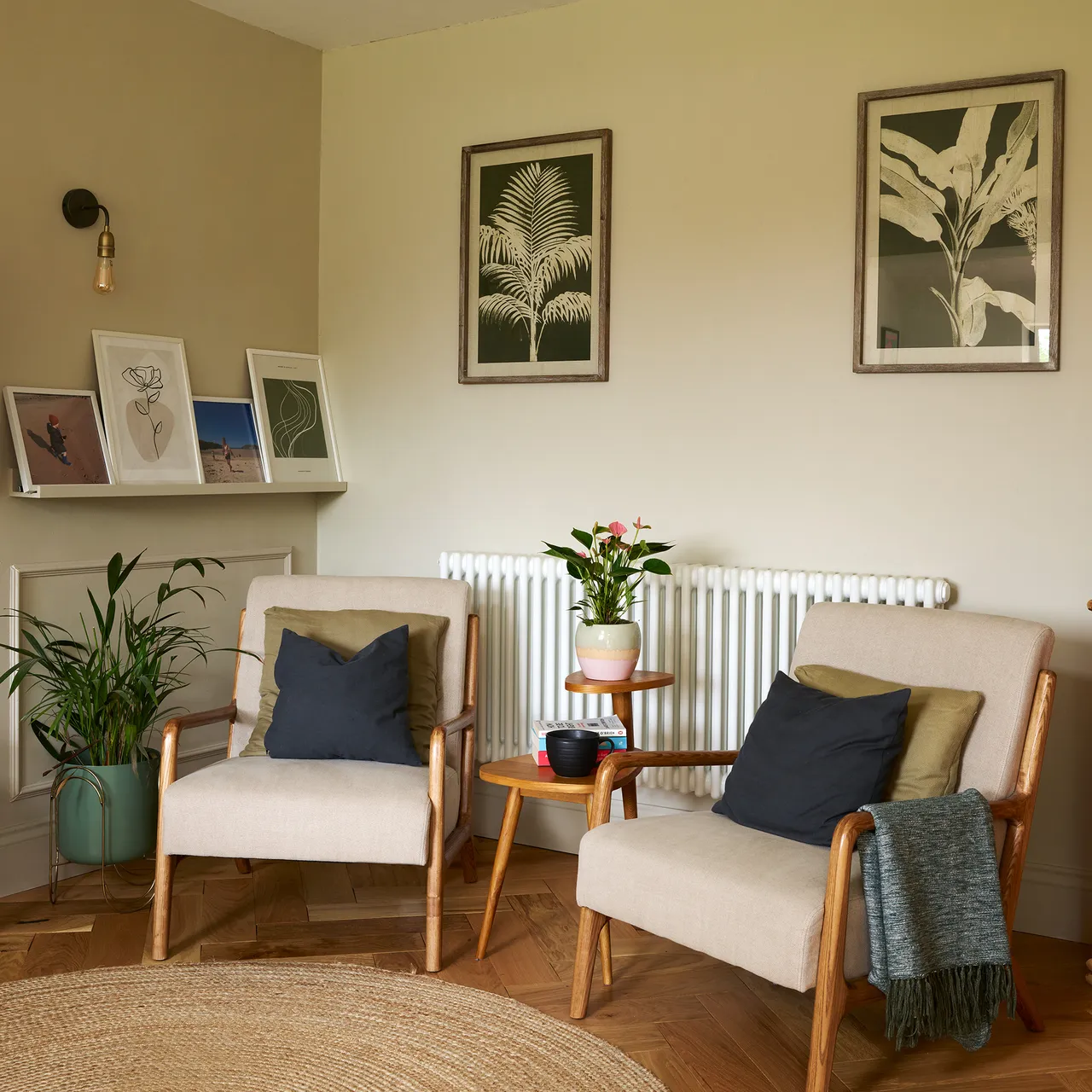 Two light armchairs sit beside a radiator and small side table