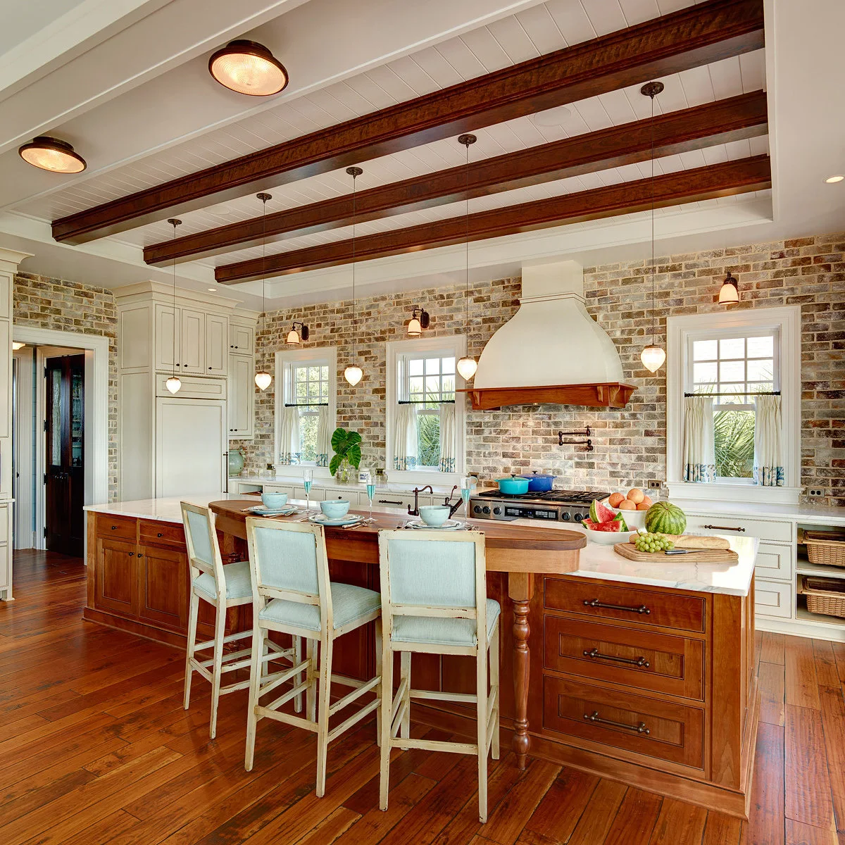 White café curtains with blue patterned hems in a brick-walled kitchen