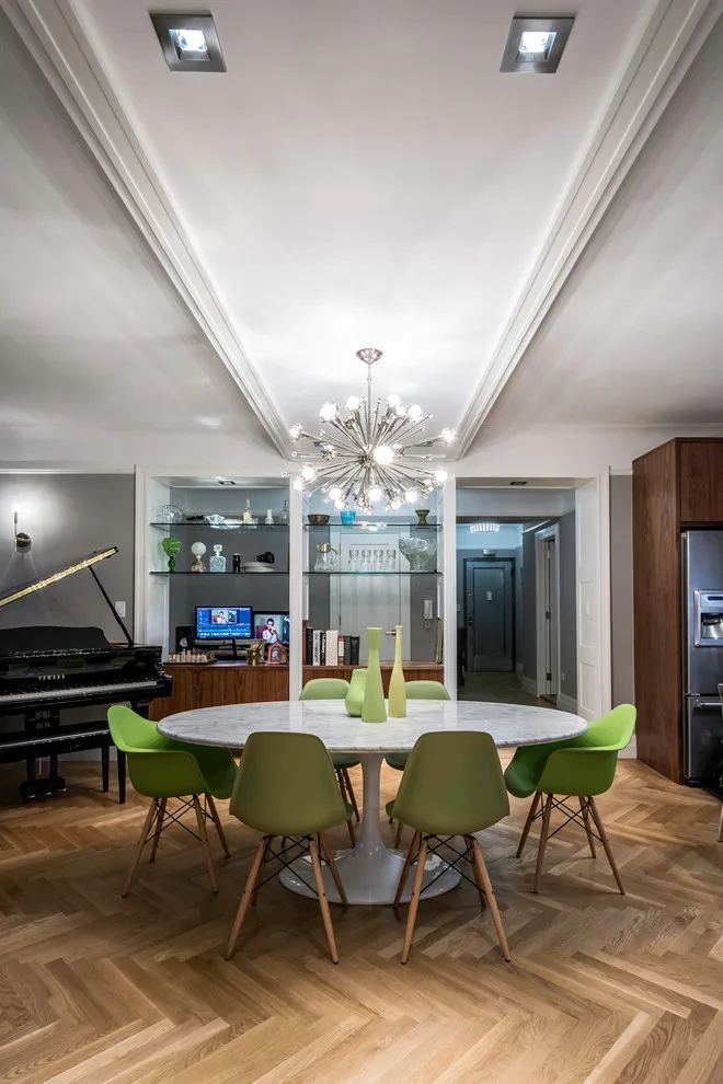 Green chairs in varying shades surround a pale oval table in an open room