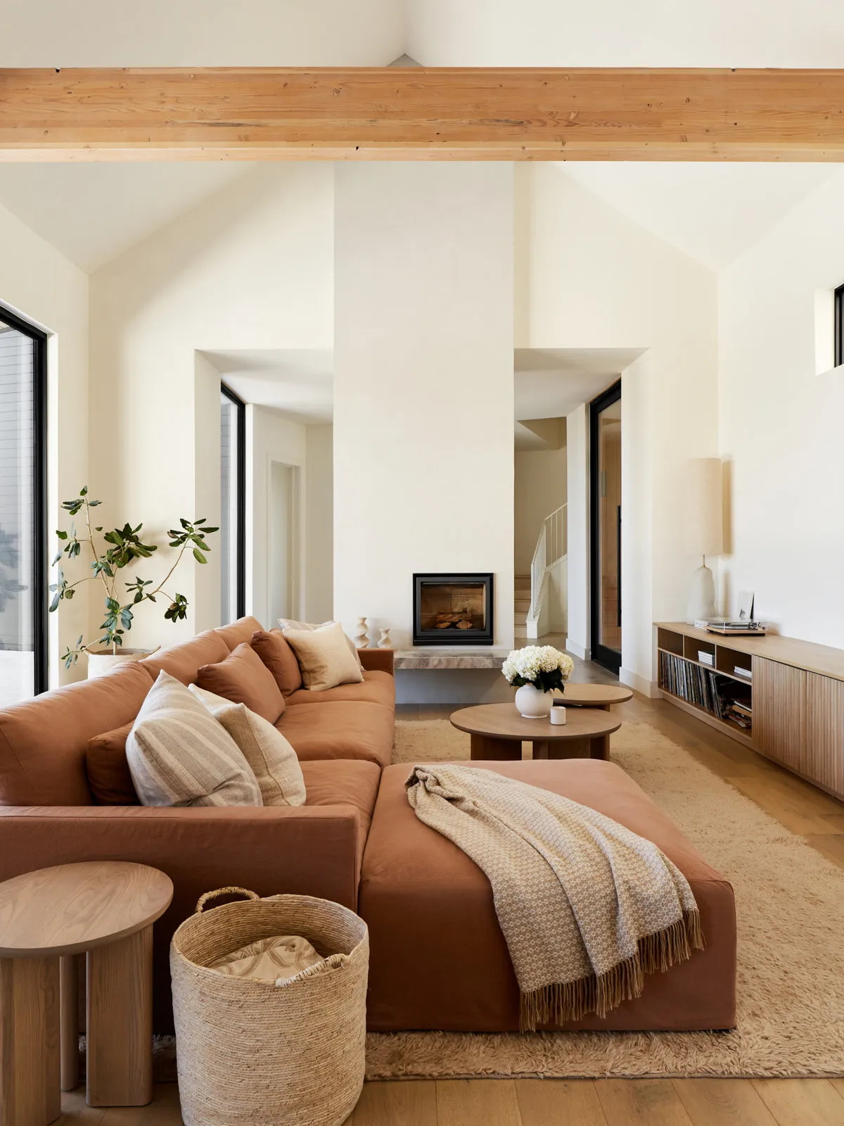 A tan sofa sits beneath pale walls beside a natural basket and light throw.