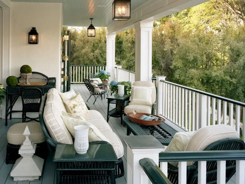 Long white porch with black woven seating, pale cushions and suspended lantern lights