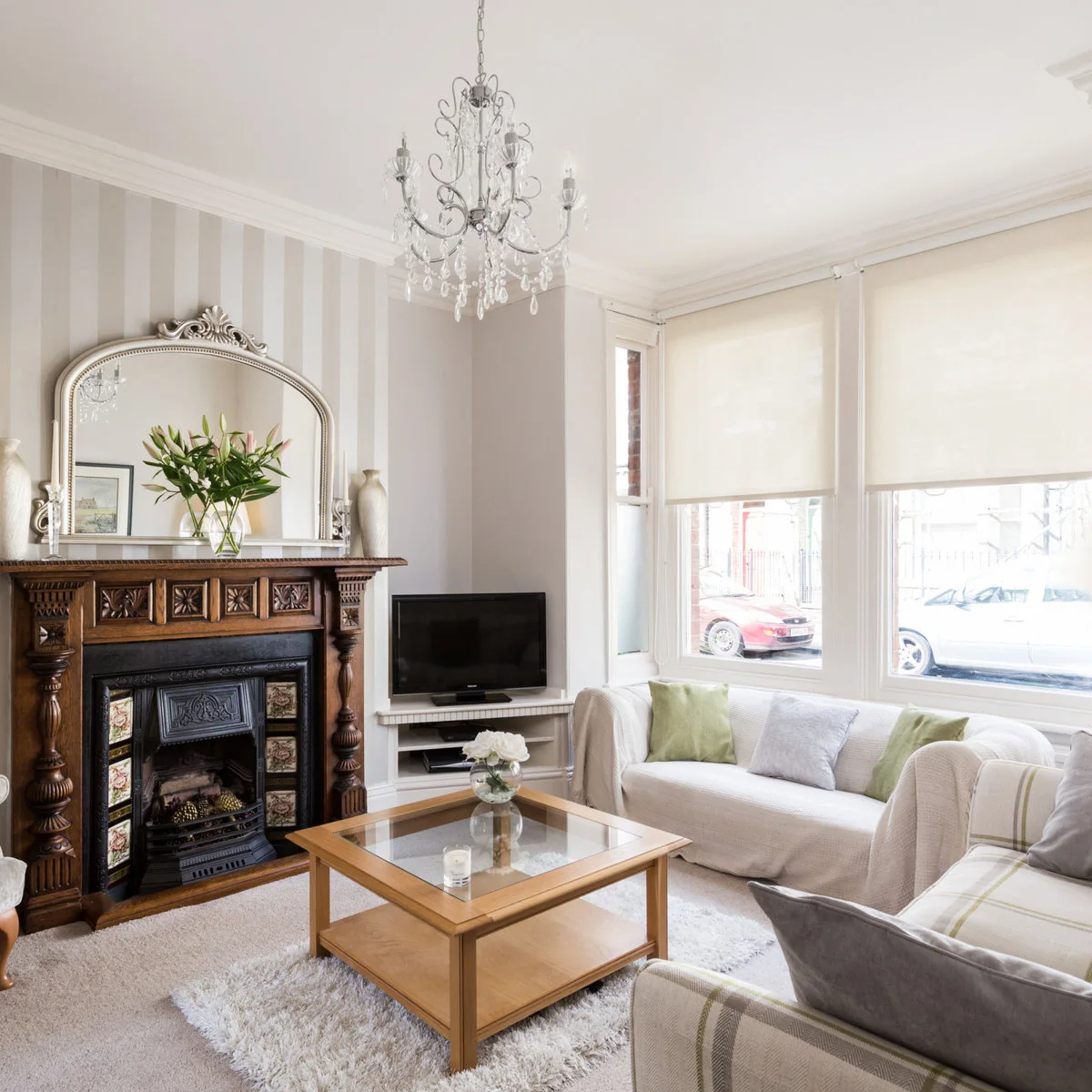 Edwardian front room with pale seating, roller blinds, striped wallpaper and a carved fireplace