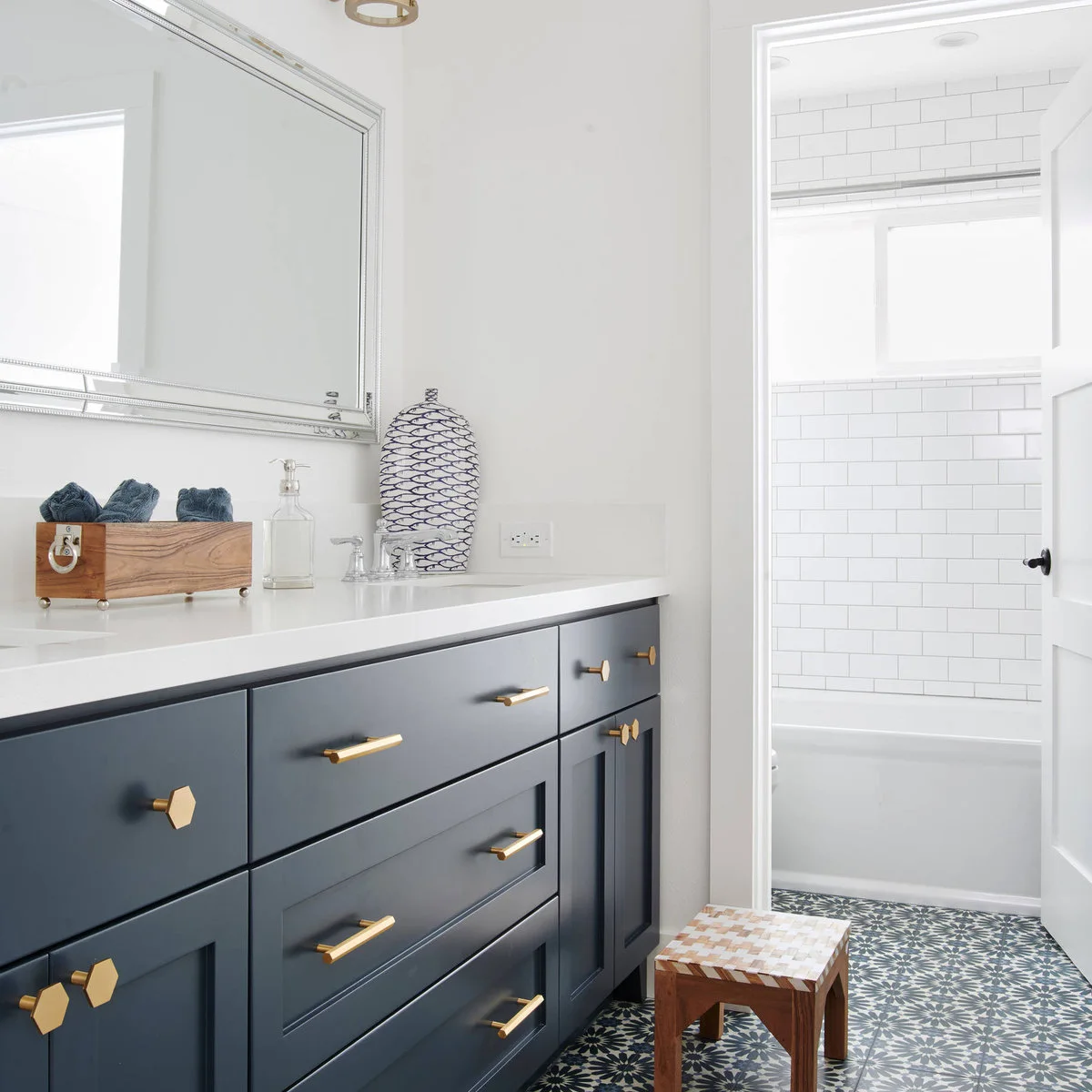 Navy vanity with rolled dark towels in a wood box and a blue-and-white patterned lidded jar.