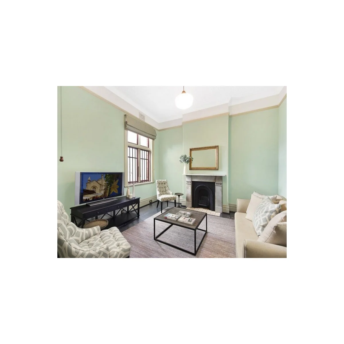Pale green Edwardian terrace sitting room with a low black media table and compact square coffee table