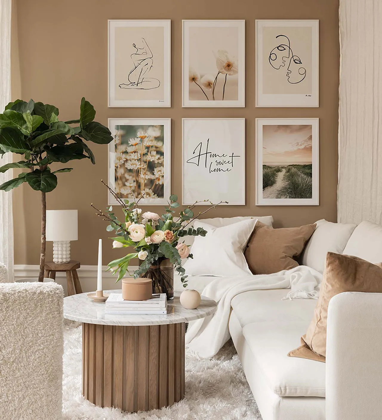 A pale sofa sits beneath a grid of framed artwork against a warm beige wall