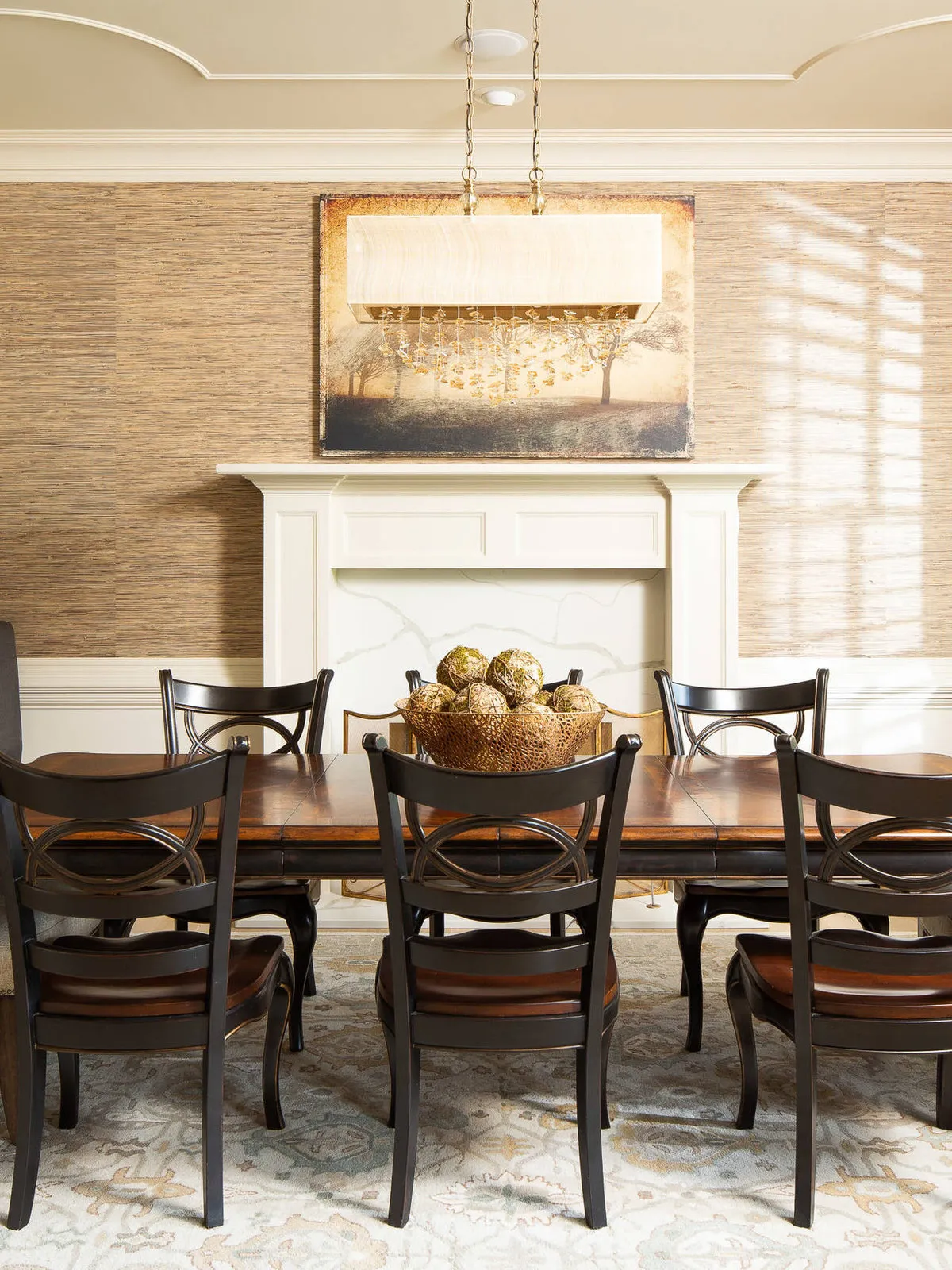 Dark cross-back chairs surround a table beneath a pale mantel and textured wall.
