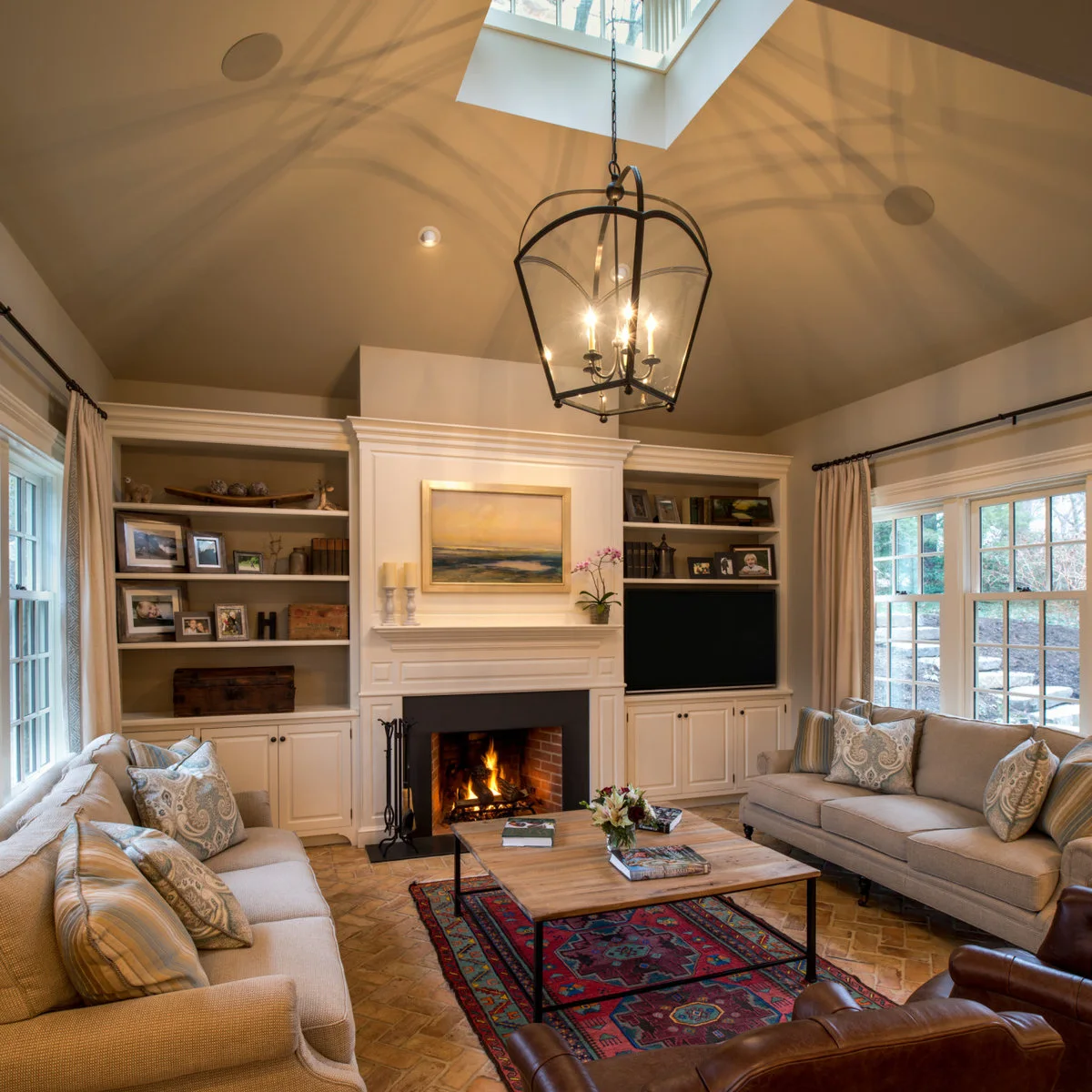 A fireplace with a landscape painting above it, a television in right-hand shelving and two sofas facing a wood coffee table.