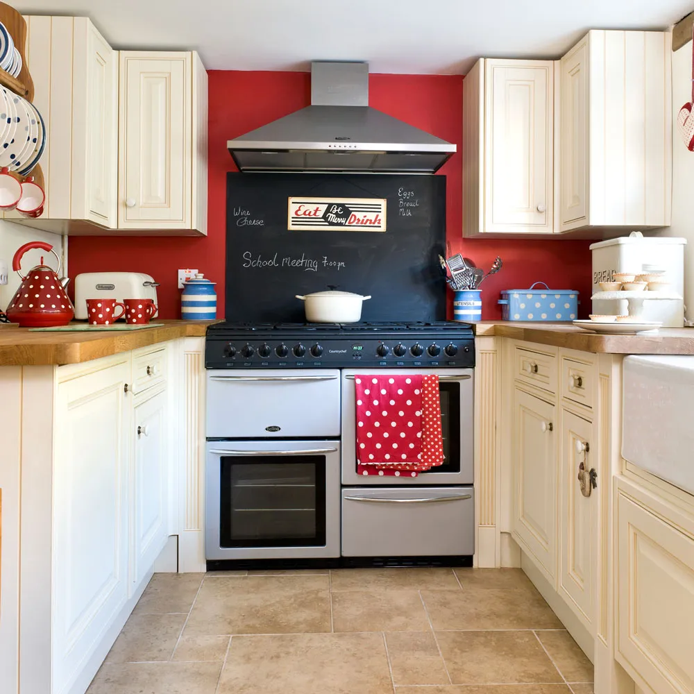 Cream cabinets frame a red wall and a dark range in a compact kitchen